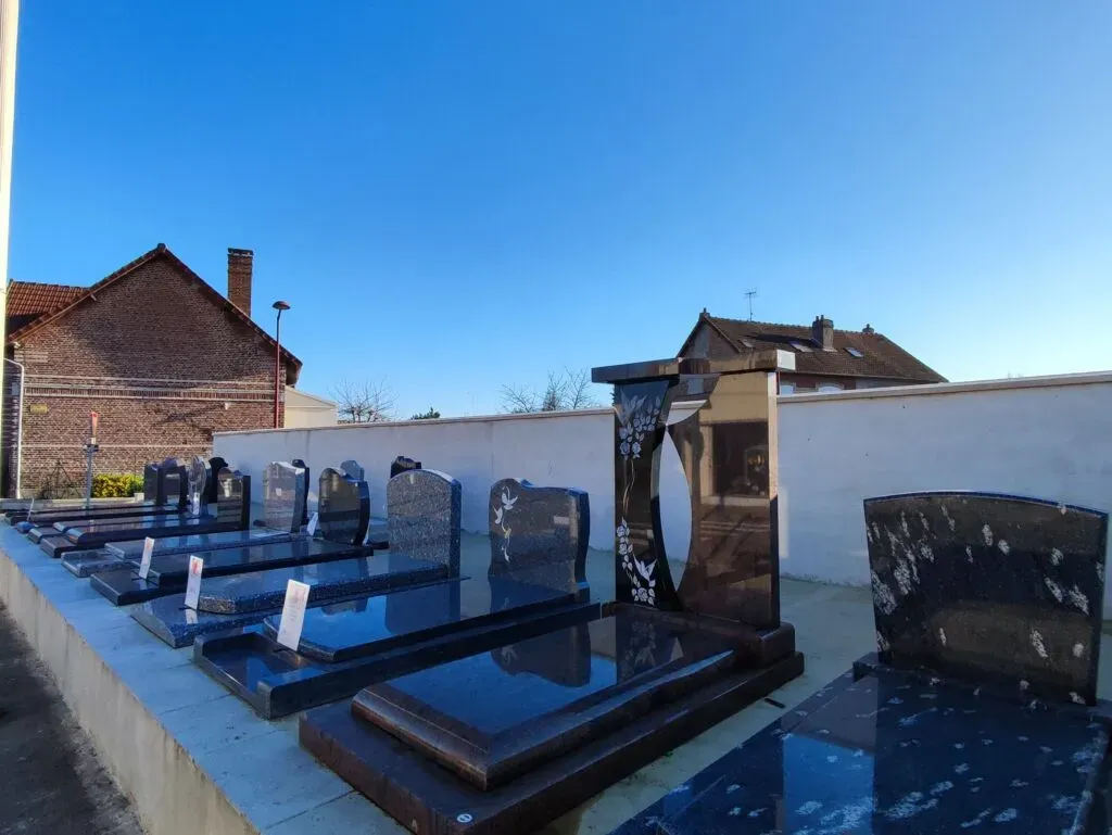 Range de monuments funéraires présentés en extérieur sous un ciel bleu.