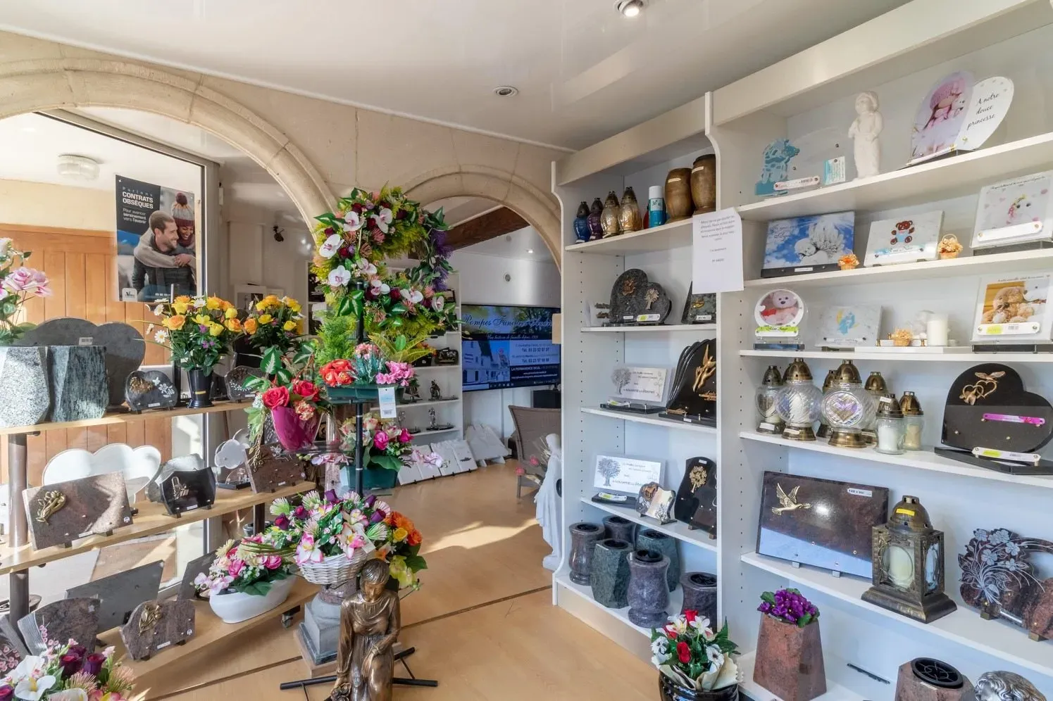Boutique funéraire exposant des fleurs artificielles, plaques et lanterne de souvenir.