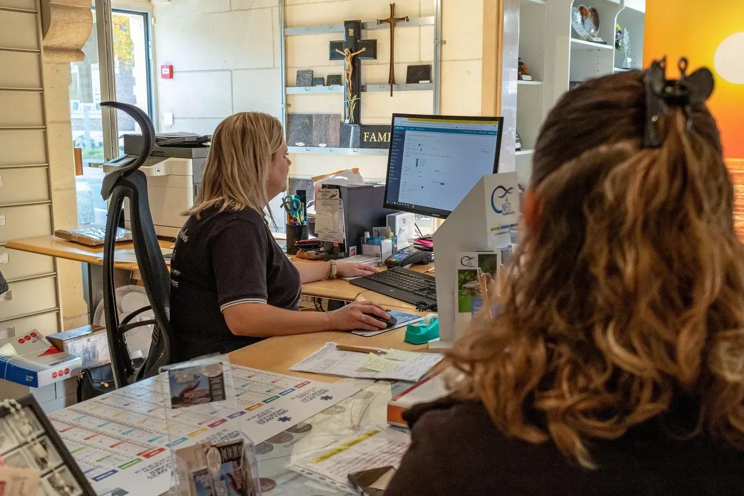 Conseillère funéraire travaillant sur un ordinateur au bureau d'accueil.